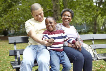 Mum, dad and son having fun on park bench