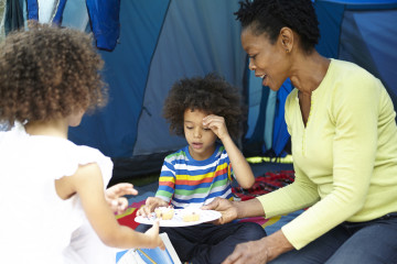 Mum, son and daughter picnic outside tent